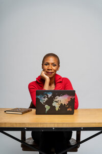 Black woman life coach in red jacket with laptop