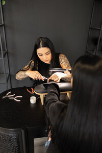 Professional brow artist focusing with magnifying lamp during client procedure. Photograph by Yucaipa branding photographer Kaitlyn Dawn Photography.