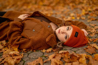 A Brookfield Central High School Student lays on a Hartland, WI road covered with Fall leaves as her senior photos are taken.