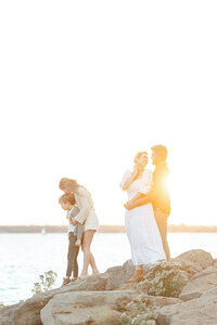 A beautiful family sunset photo as they are posing on rocks at a local DFW lake for their photographer.