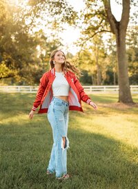 Senior portrait in downtown Magnolia Springs, Alabama — twirling while wearing her letterman jacket showing a care free spirit.