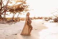 Folly Beach Maternity Photographer -- Pregnant woman poses for Maternity Photos at the Lighthouse Inlet Heritage Preserve on Folly Beach with iconic views of the Morris Island Lighthouse in the distance.