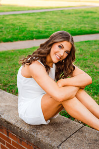 Senior sitting on a bench on the MTSU campus smiling at the camera while leaning forward