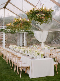 A green and white themed wedding tablescape with greenery chandliers in carmel valley