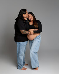Pregnant mom sharing an intimate moment with her partner, who gently kisses her cheek while holding her belly during a maternity session in Yucaipa by Kaitlyn Dawn Photography.