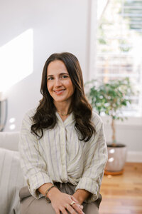 Woman sitting on a couch arm and smiling for her bay area branding session for her therapy practice