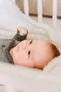 A newborn boy looks up from his crib.