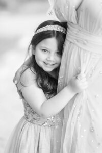 Black and white portrait of the DiLorio family’s daughter smiling while hugging her mother in a tender outdoor Las Vegas photography session.