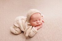 Newborn baby sleeping on a soft blanket in a neutral omakase studio portrait session