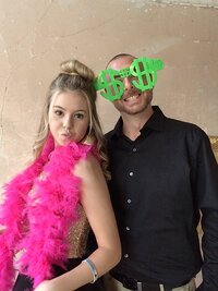 Girl wearing a pink boa and guy wearing oversized dollar sign glasses