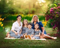 Grandmother, mother and children sitting on a blanket in spring flowers during a family photography session in Eastern North Carolina
