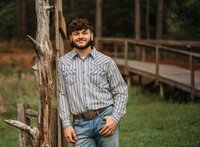Senior portrait at Circle B Lake in Wilmer, Alabama — hip-up leaning against an old wooden
doorway.