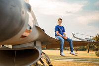 Senior portrait at Battleship Memorial Park in Mobile, Alabama— sitting on the wind of an f16 fighter jet.