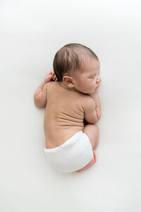 Newborn boy curled on his side sleeping during a studio session