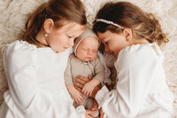Newborn Pictures in Charleston - Siblings embrace their infant baby brother during Newborn Pictures at Holy City Babies Newborn Photography Studio in Charleston, SC.