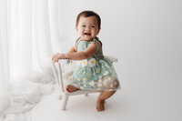 Charleston Cake Smash Photographer - Baby smiles at the camera during Milestone Portrait Session at Holy City Babies in Charleston, SC.