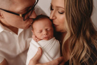 Newborn Photographer in Charleston - Parents embrace their infant during Newborn Portrait Session in Charleston, SC.