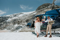 bride and groom in front of helicopter in whistler