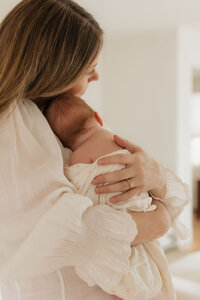 mom-holding-newborn-over-shoulder-cotton-dress-in-home-boulder-photography-103