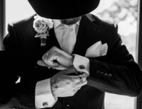 Detail shot of groom fixing his cufflink at Loco Lake Event Venue captured by Graceful Ray Photography in Fort Worth Texas