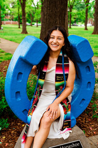 College senior wearing custom stole and cords sitting in the MTSU horseshoe