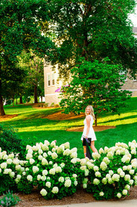 Senior girl walking across the Trevecca Nazarene campus smiling over shoulder in the summertime