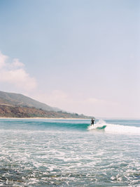 A photograph of a man surfing at Leo Carrilo beach in Malibu, CA