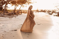 Folly Beach Maternity Photographer -- Pregnant woman poses for Maternity Photos at the Lighthouse Inlet Heritage Preserve on Folly Beach with iconic views of the Morris Island Lighthouse in the distance.