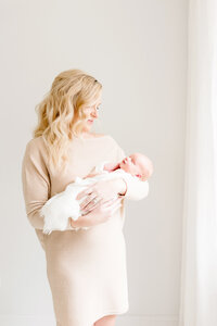 Mother holding baby in window light