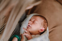 This is a top down view of a newborn baby sleeping in his mother's arms.