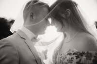 a bride and groom stand under the brides veil during their couples portraits with shelly voss