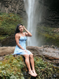 Clackamas high school senior sitting on rock at latourell falls with the falls cascading behind her in the Columbia River Gorge.