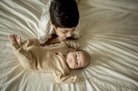 A young boy admires his new brother at an in home session.