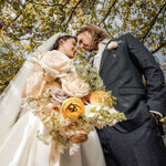 Romantic bride and groom portrait under blooming spring trees at Hazlewood Castle, Yorkshire, holding pastel wedding bouquet, captured by Yorkshire wedding photographer.