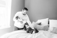 dad holds newborn and toddler laughs on bed