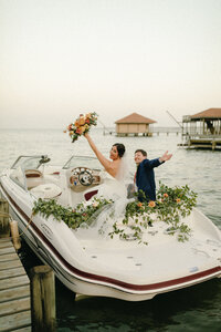 bride and groom waving from boat