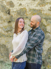 Couple posing for an engagement portrait in front of an old brick wall during a romantic spring engagement photography