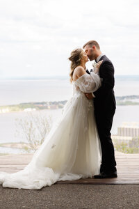A newlywed couple shares a kiss overlooking Lake Superior