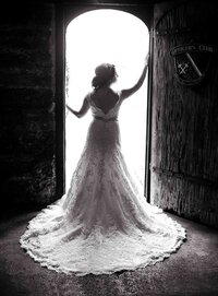 Professional photography by Nature's Child Photography: St. Augustine wedding capturing a bride silhouetted in a historic doorway, her detailed lace train flowing behind as natural light pours in from outside.