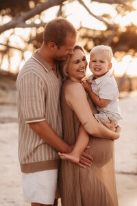Folly Beach Maternity Photographer -- Pregnant woman poses for Maternity Photos at the Lighthouse Inlet Heritage Preserve on Folly Beach with iconic views of the Morris Island Lighthouse in the distance.