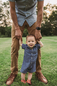 toddler holding dad's hands to stand