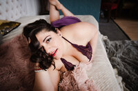 woman laying on her stomach in purple lingerie  at the boudoir studio in Minneapolis Mn