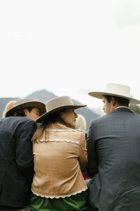 Two men and a woman in cowboy hats sit chatting as they wait for a wedding ceremony to begin in Telluride, Colorado.