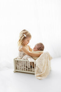 Big sister holds her new baby brother during his newborn photo session near New Ulm, Minnesota.