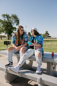 Two friends sitting on a picnic table laughing together.