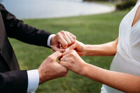 Close of wedding rings as bride and groom hold hands