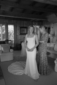 Bride is helped into wedding dress in a cottage on Nantucket.