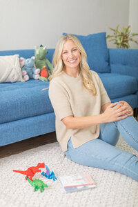 Female business owner sitting on a floor near a couch during a relaxed Ventura County brand photography session.