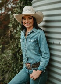 Senior portrait at Triple T Farms in Fruitdale, Alabama — leaning against a silo in a denim outfit.
