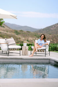 Lifestyle personal brand photography of a female entrepreneur relaxing poolside at a modern California home